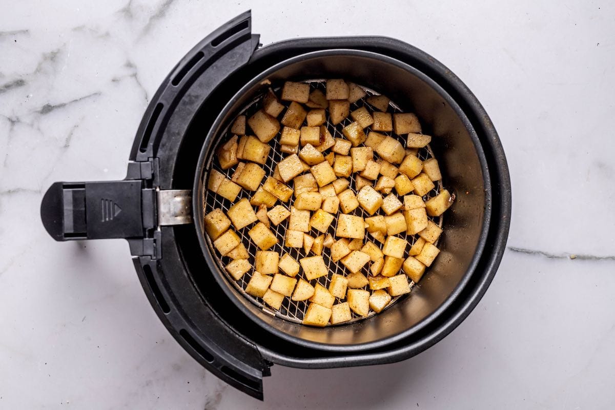 seasoned apples in the air fryer basket.