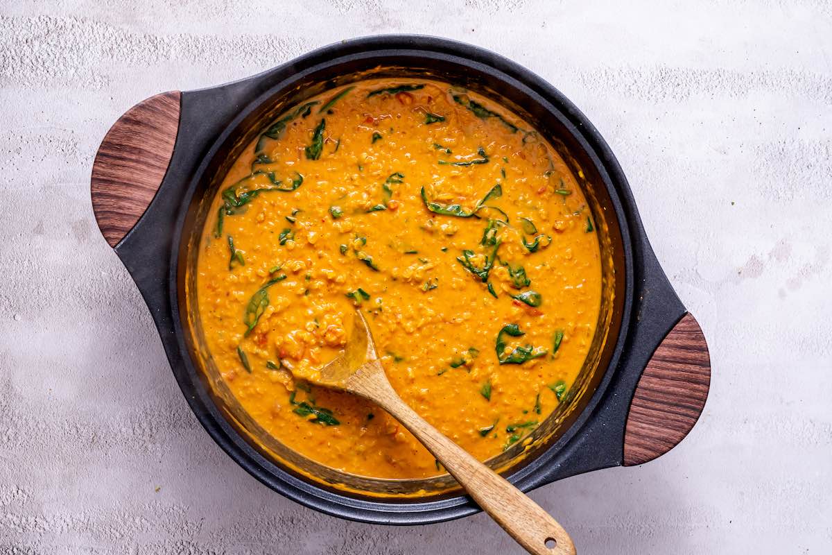 lentils, spinach, and coconut milk in a pot.