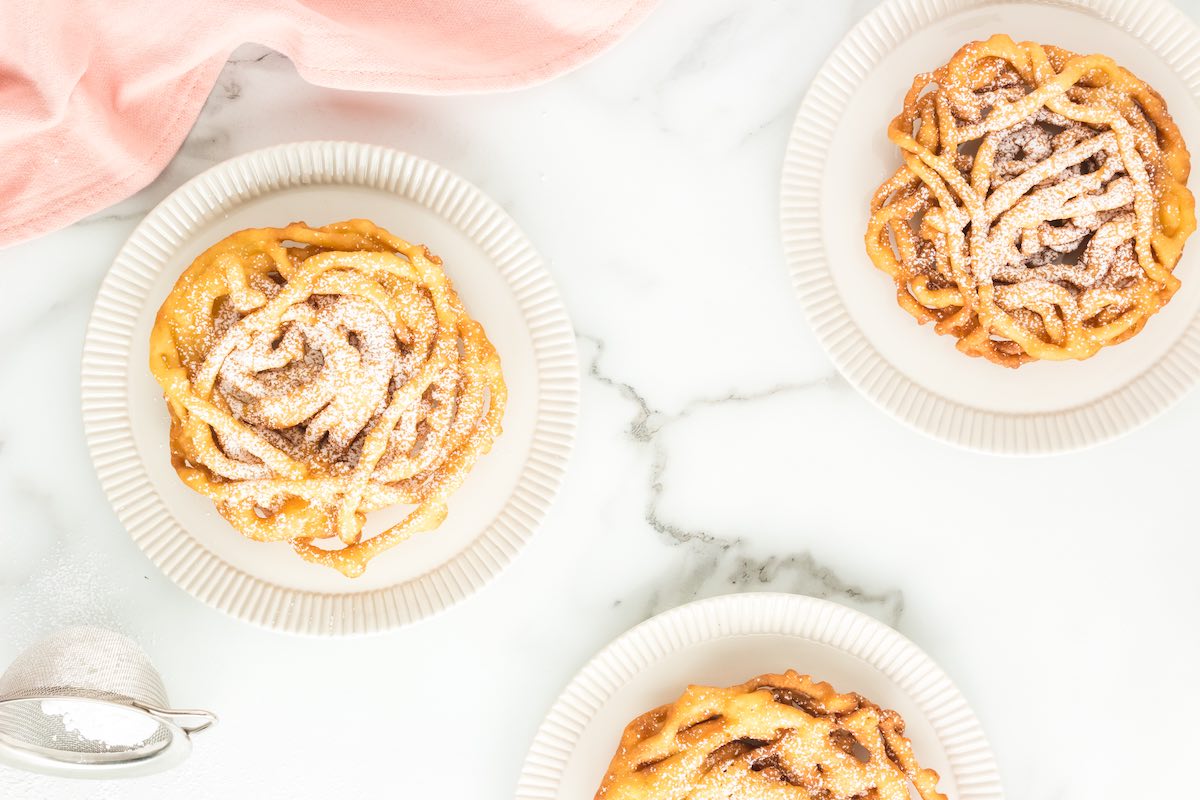 homemade funnel cakes with powdered sugar on top.