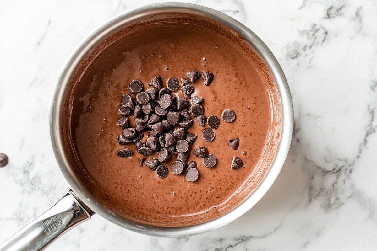 milk mixture in saucepan with chocolate chips on top.