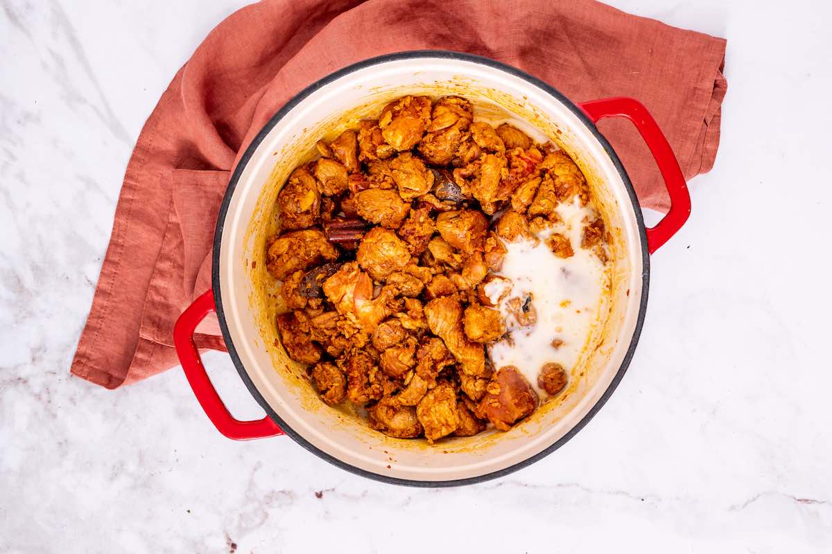 yogurt, lamb, and spices simmering in a skillet.