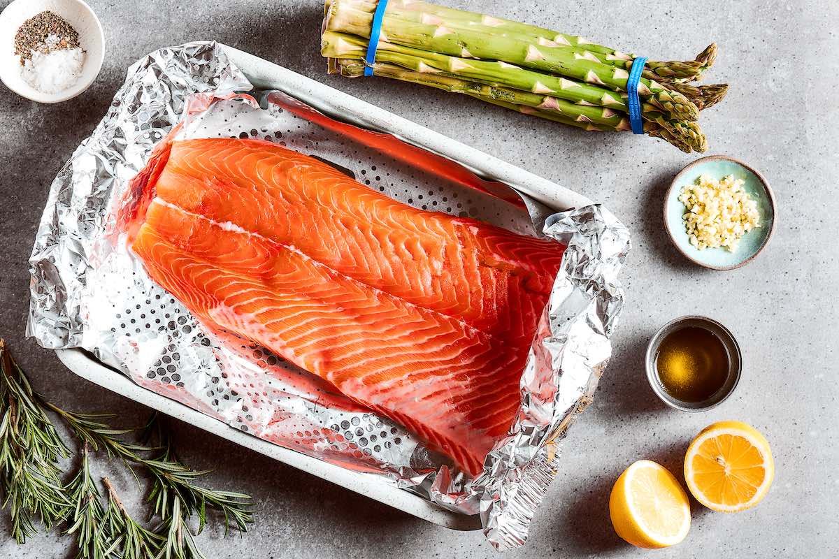 raw salmon fillet on tin foil in a baking dish.