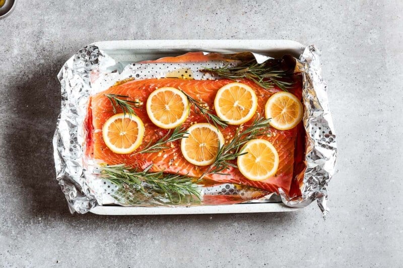 seasoned salmon with lemon slices and fresh Rosemary on top.