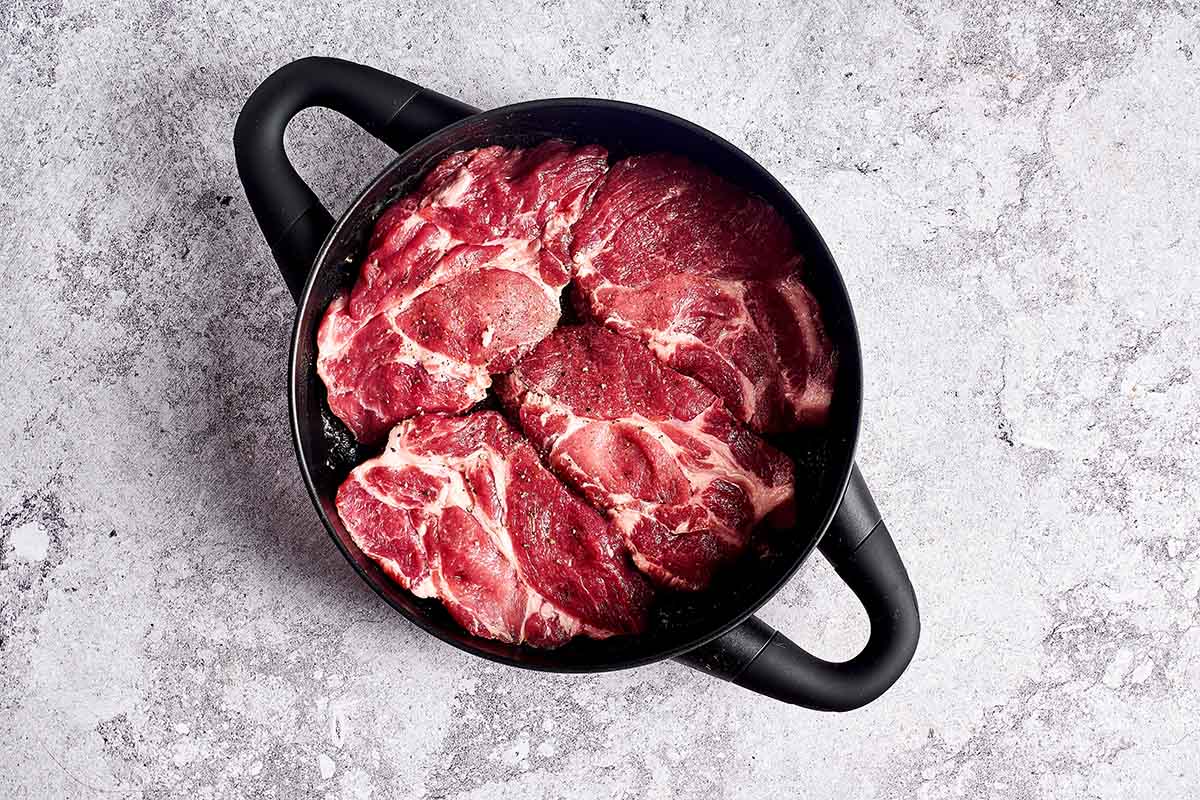 raw steaks in a skillet.