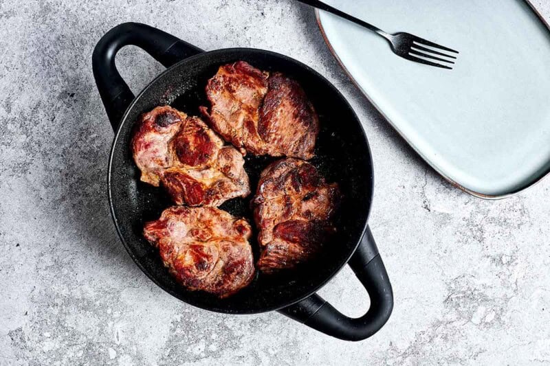 seared pork steaks in a skillet.