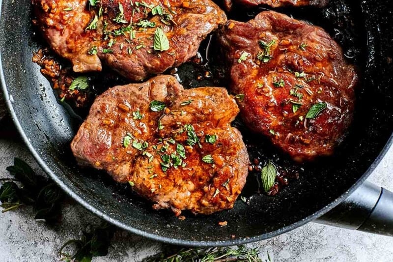 pork steaks with fresh herbs on top.