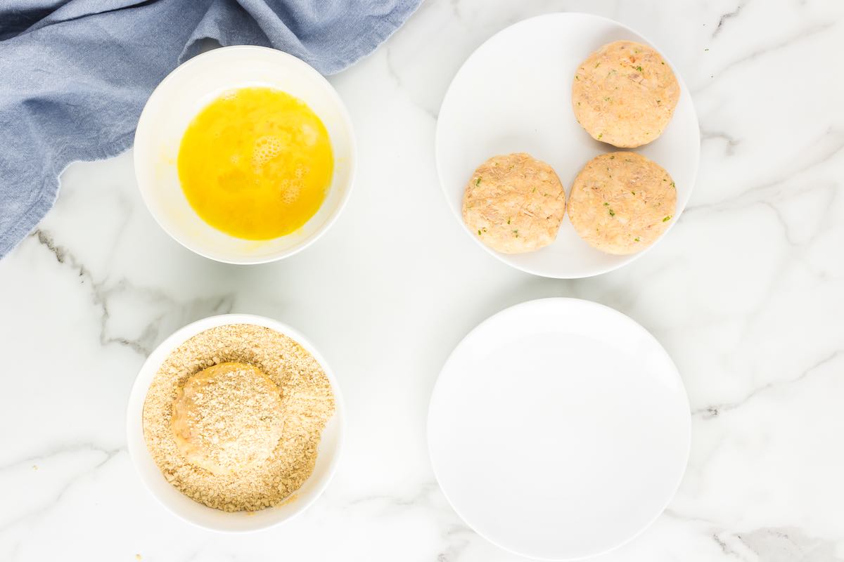 tuna mixture being dipped in eggs and bread crumbs.