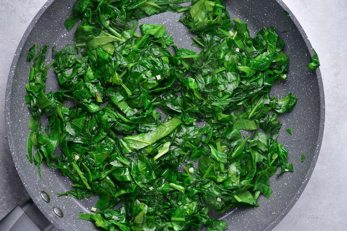 sauteing spinach in a skillet.