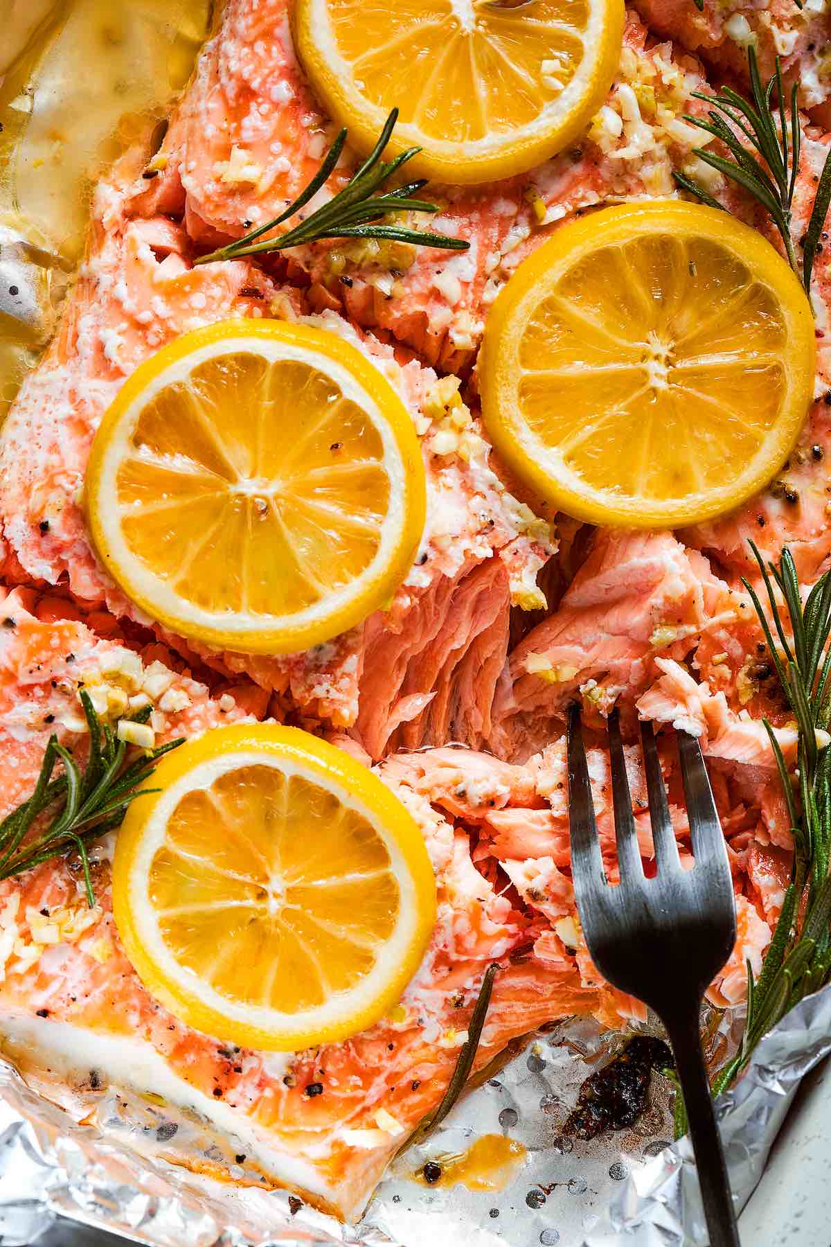 oven baked salmon in foil with sliced lemons on top.