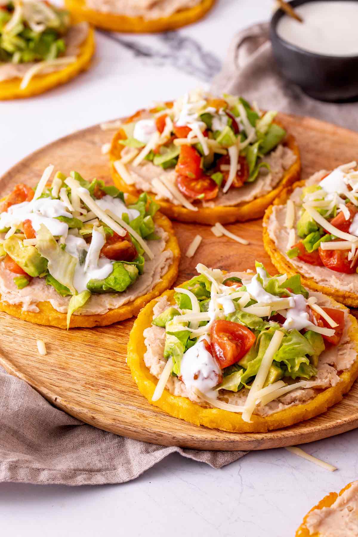 picaditas topped with lettuce, tomatoes, shredded cheese, and crema.