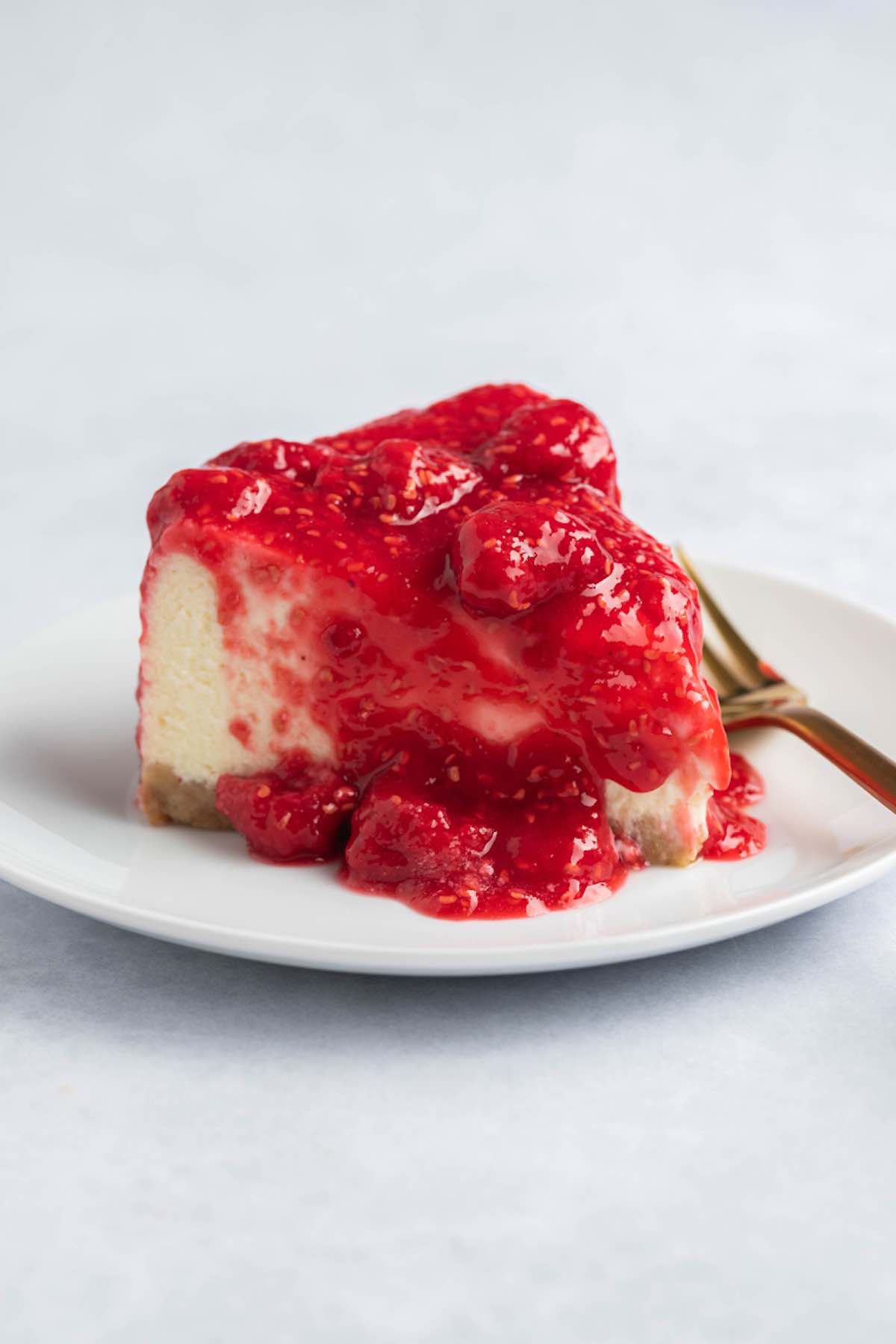 slice of raspberry cheesecake on a white plate.