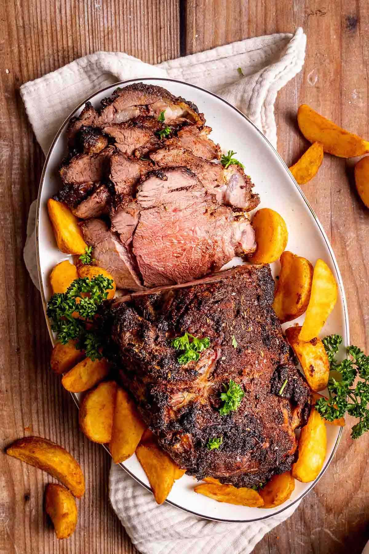 ribeye roast on a dish with roasted potatoes.