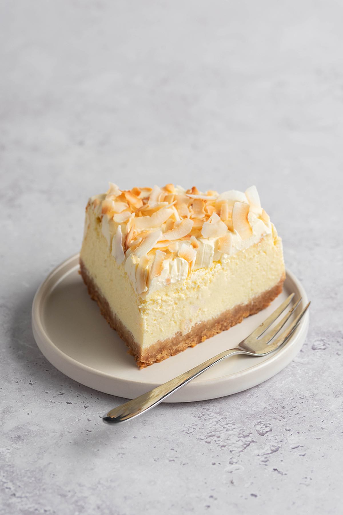 slice of coconut cheesecake on a white plate.