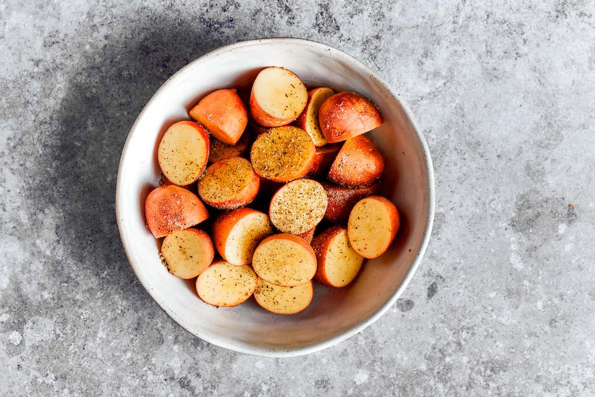 seasoned raw potatoes in a bowl.