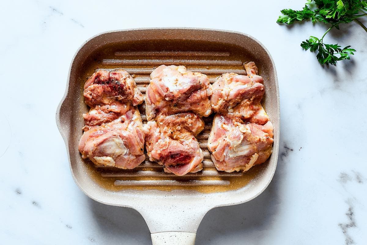 raw marinated chicken thighs on the grill.