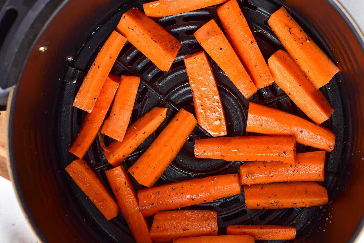 seasoned raw carrots in the air fryer basket.