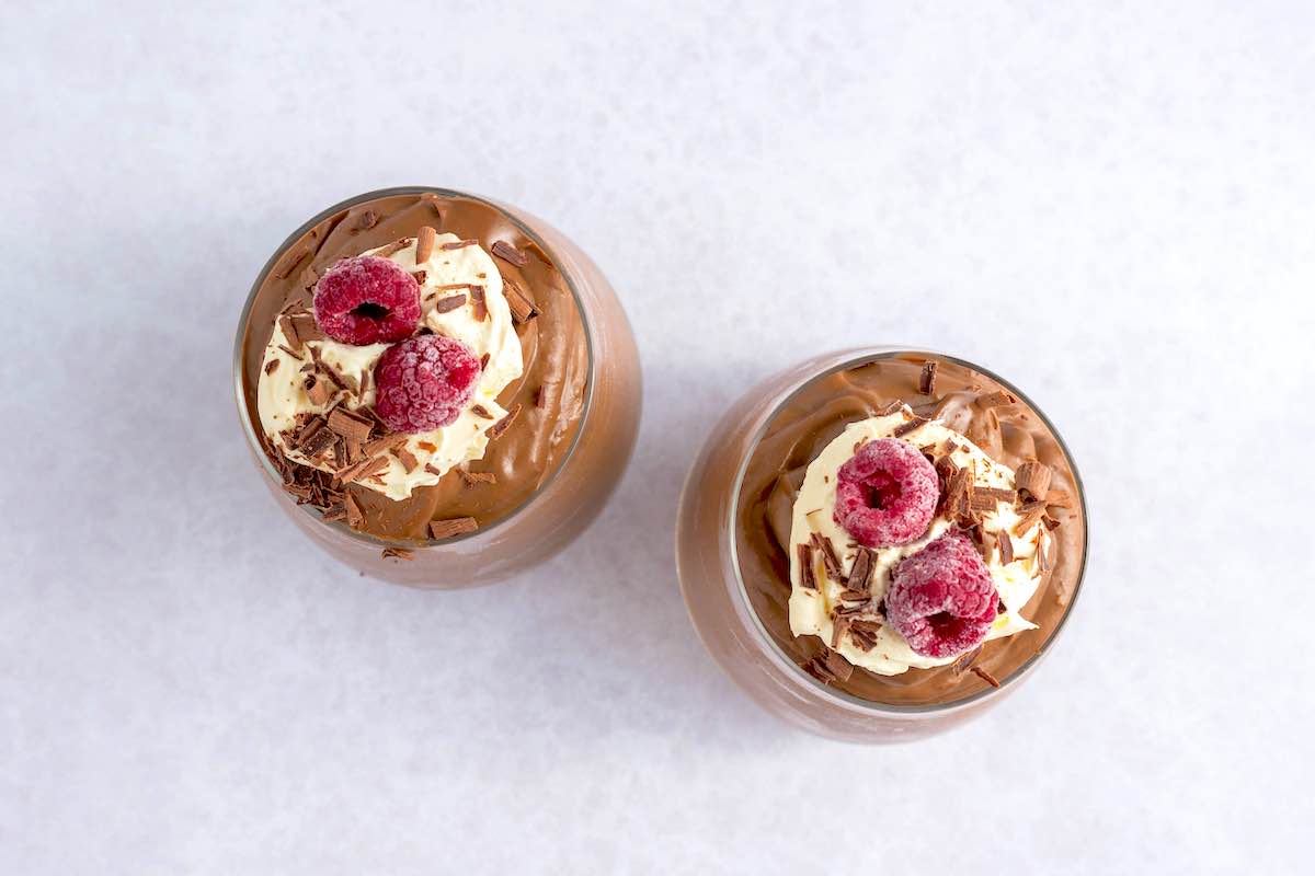 assembled chocolate mousse in glasses with cream on top.