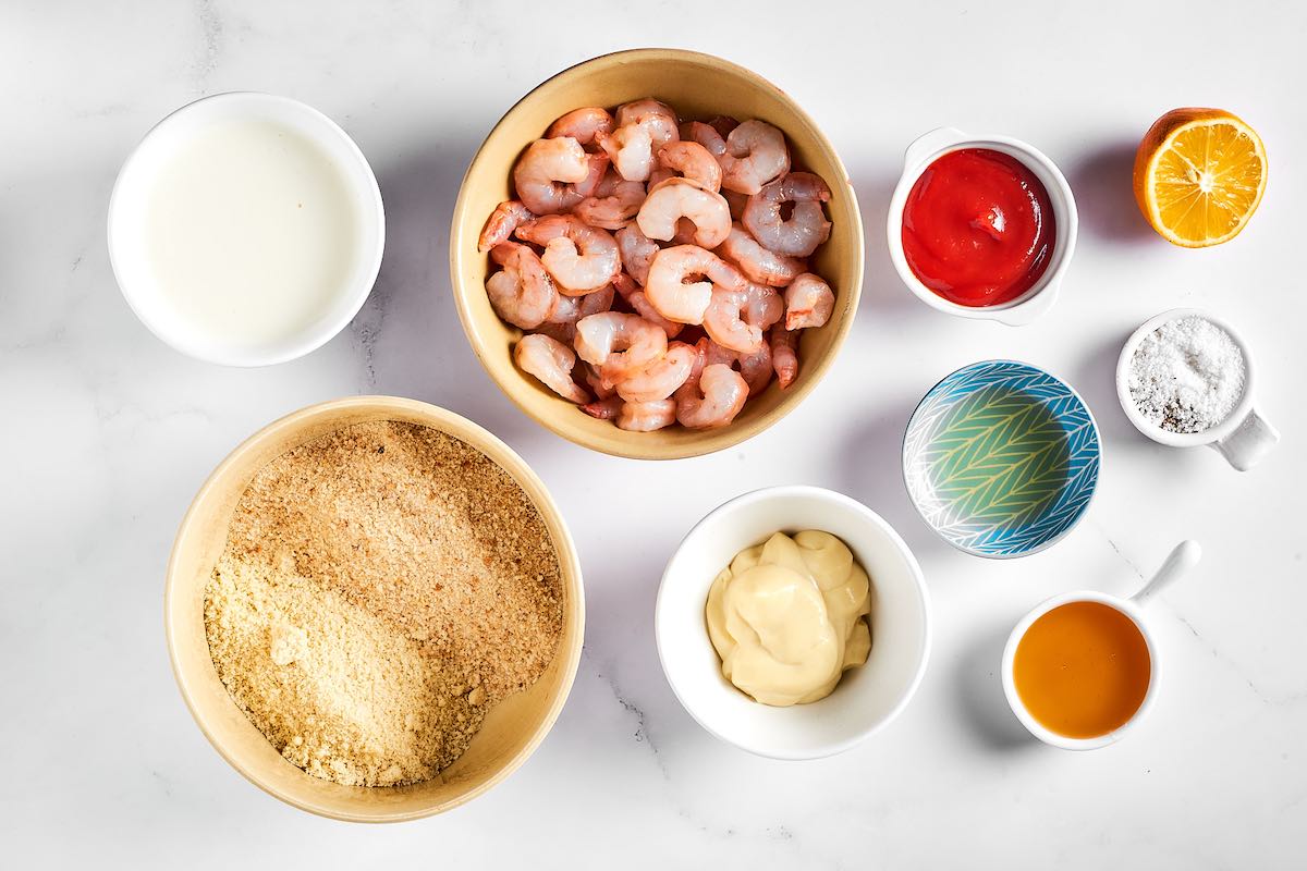 raw shrimp and breading station in bowls.