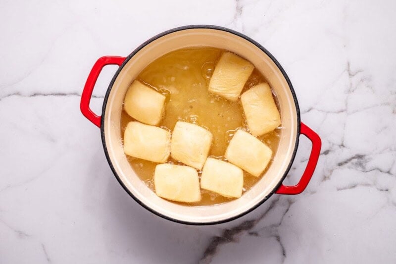 beignets frying in a pot.