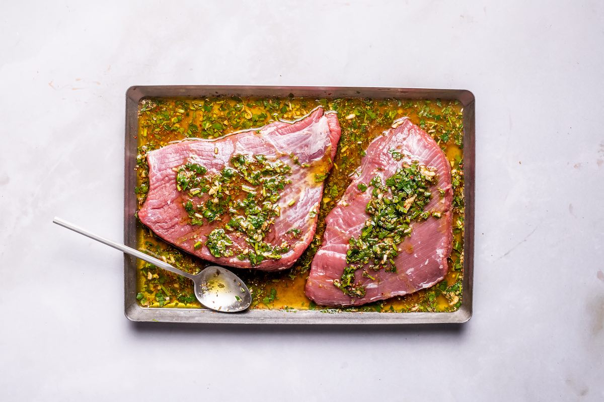 raw steaks marinating in marinade.