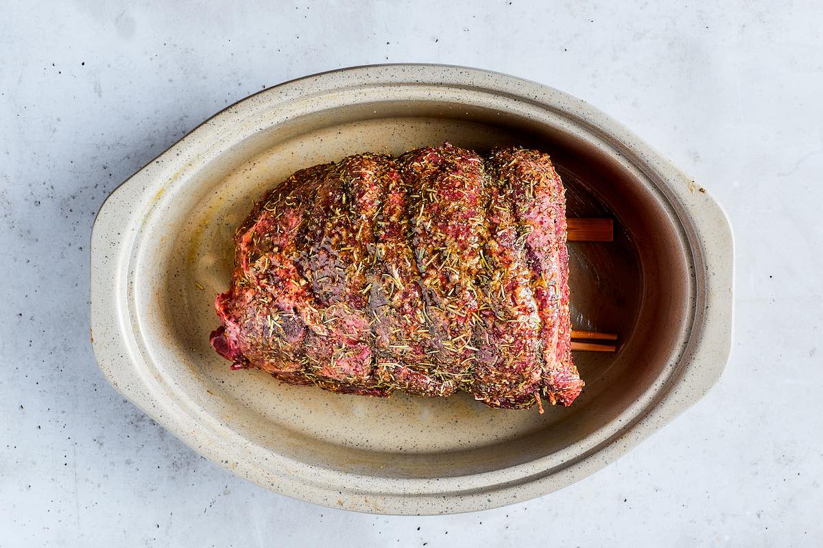 seasoned raw beef roast on a roasting rack.