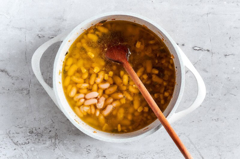 beans, broth, and vegetables simmering in pot.