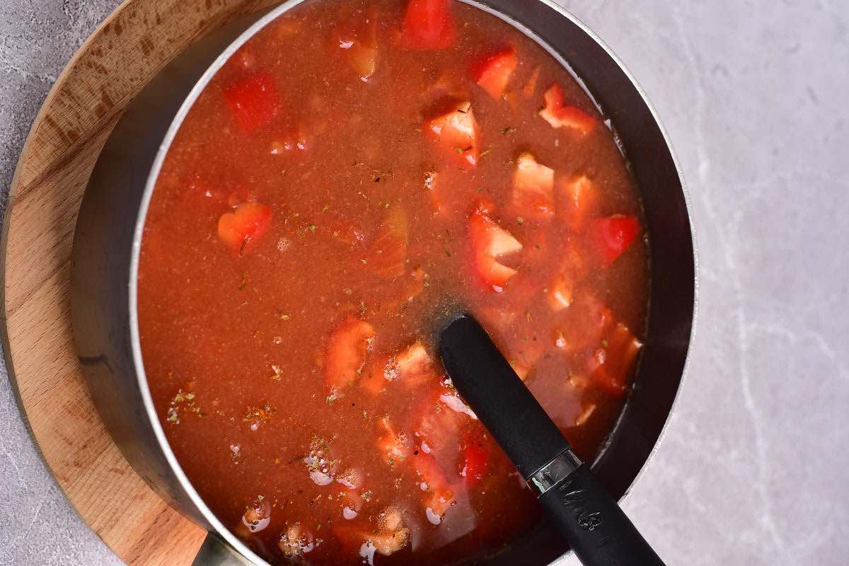 tomatoes, broth, and ground beef simmering in a pot.