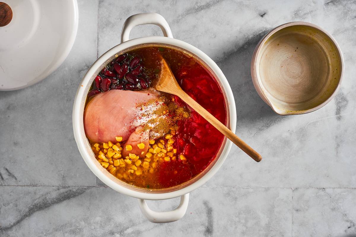 raw chicken, corn, and beans added to soup pot.