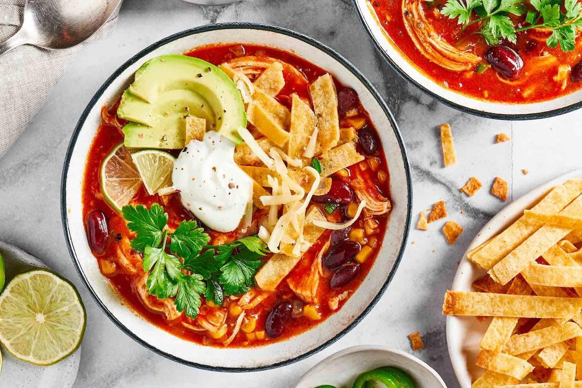 Mexican soup with tortilla strips, avocado, and sour cream on top.