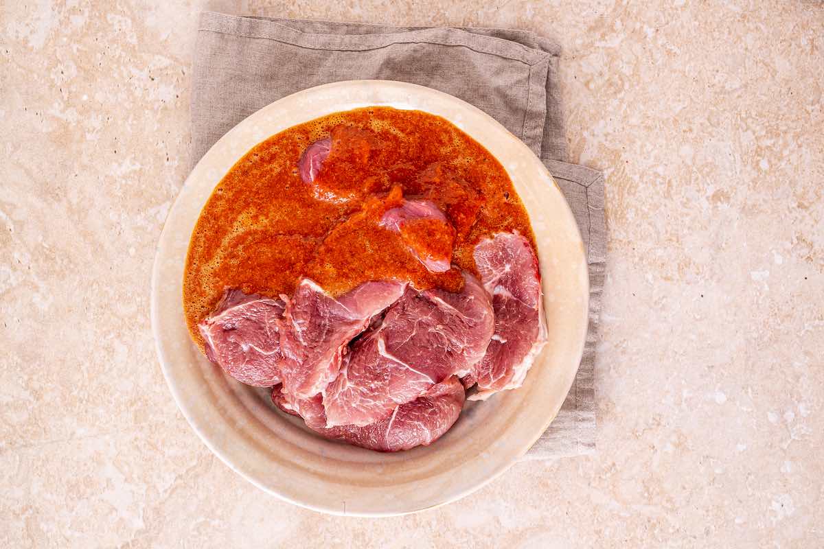 pork shoulder with marinade in a bowl.