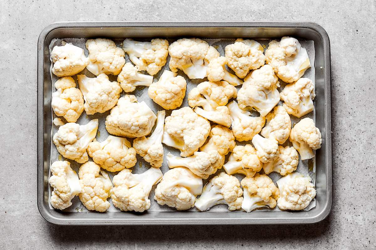 raw cauliflower florets on a roasting pan.