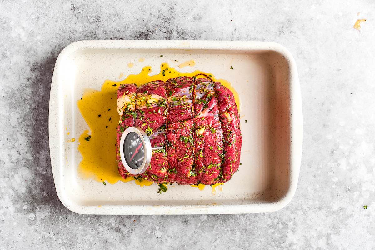 seasoned raw rump with meat thermometer in it.