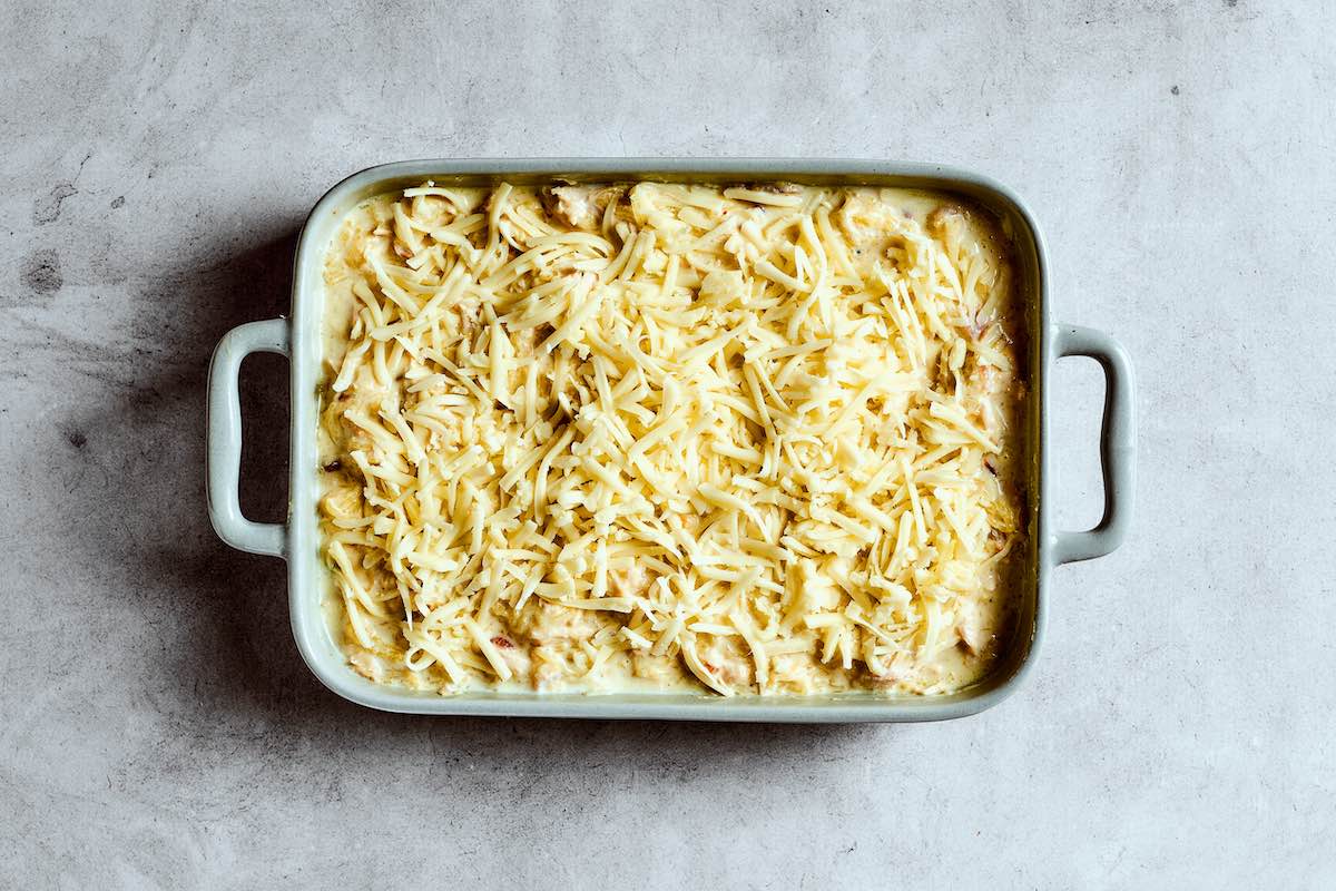 assembled spaghetti squash casserole with shredded cheese on top.