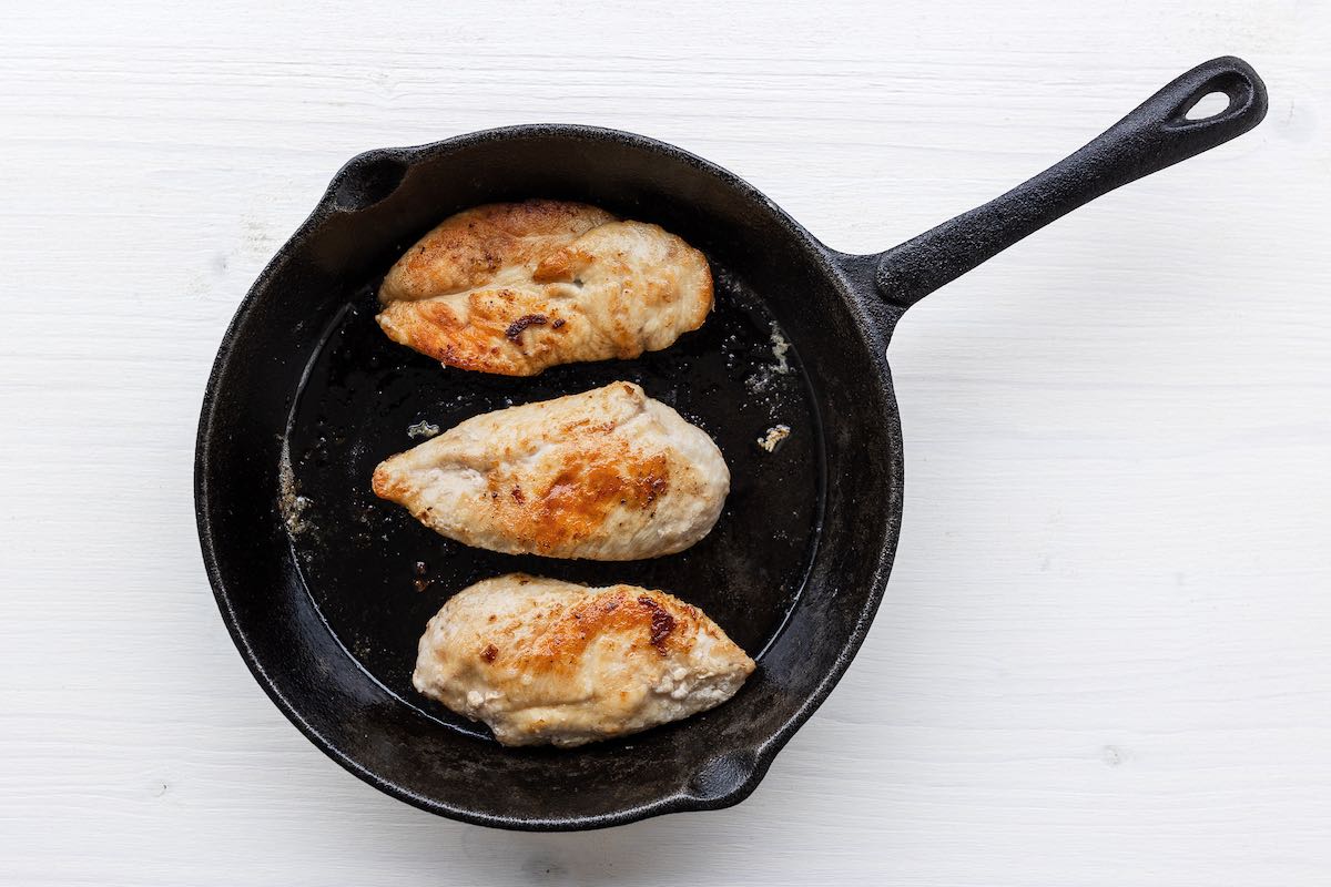 chicken breasts cooking in a skillet.