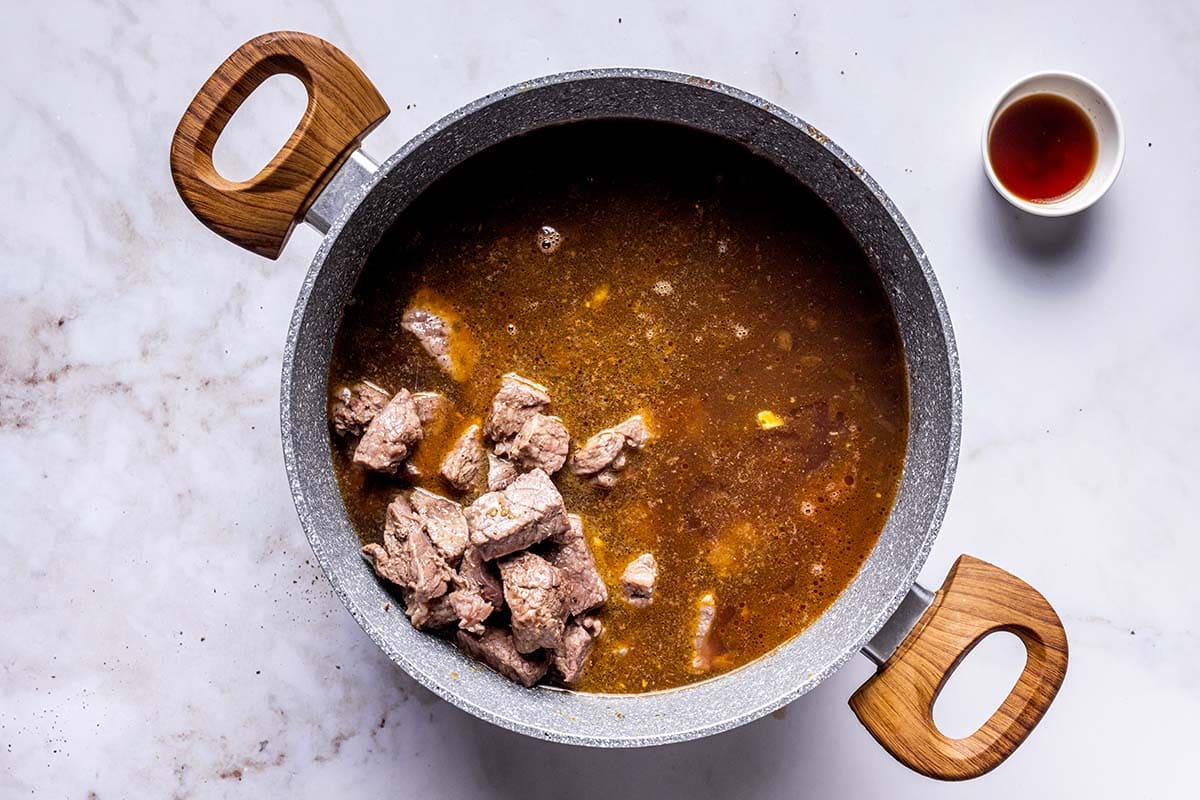 cooked chuck beef in pot with broth and seasonings.