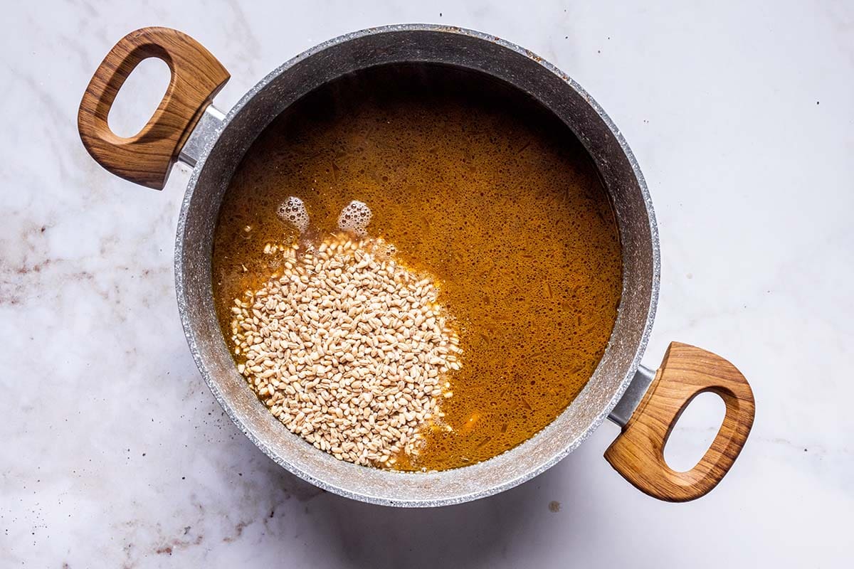 adding barley to the soup pot.