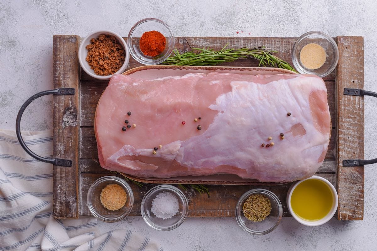 raw pork loin with bowls of seasoning.