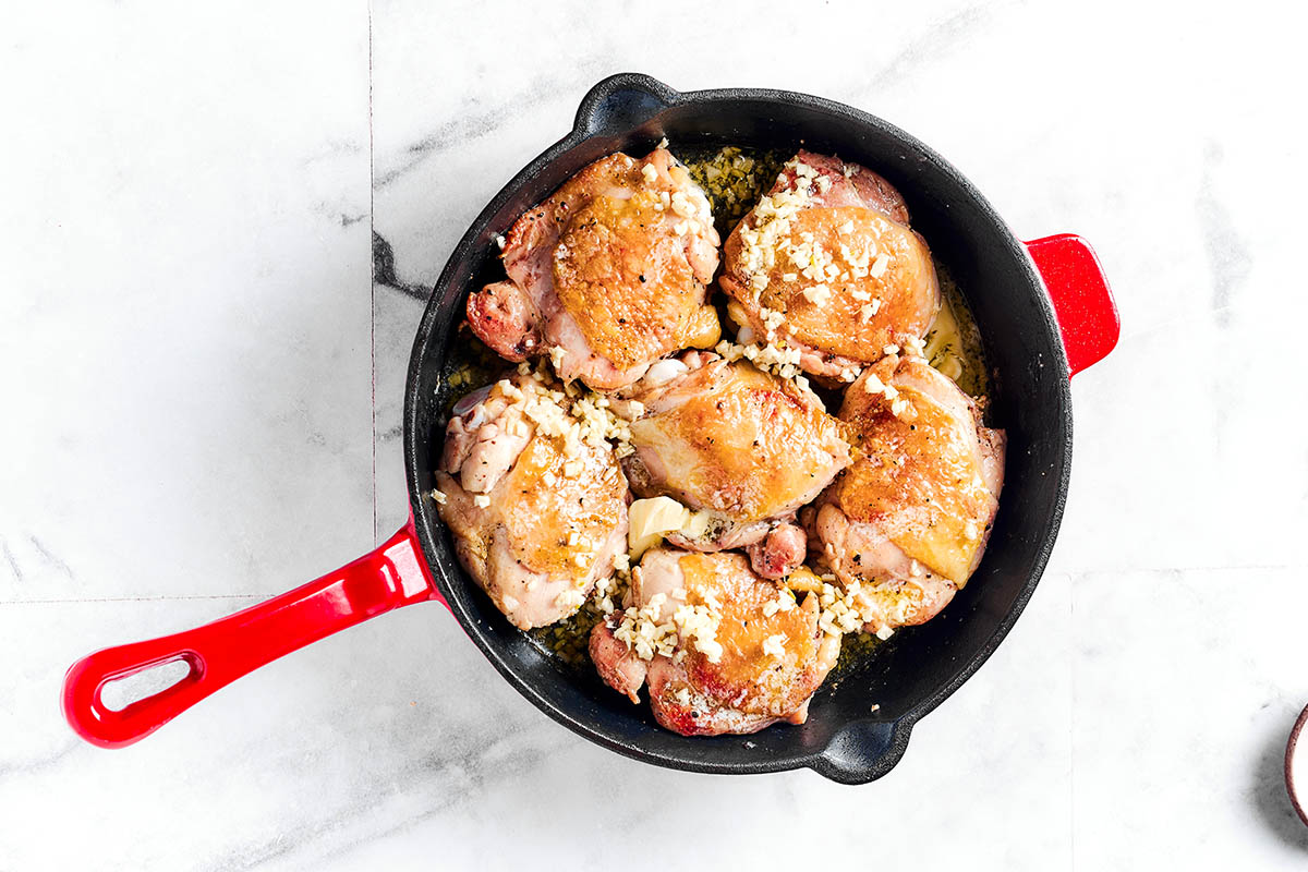 searing chicken thighs in a skillet.