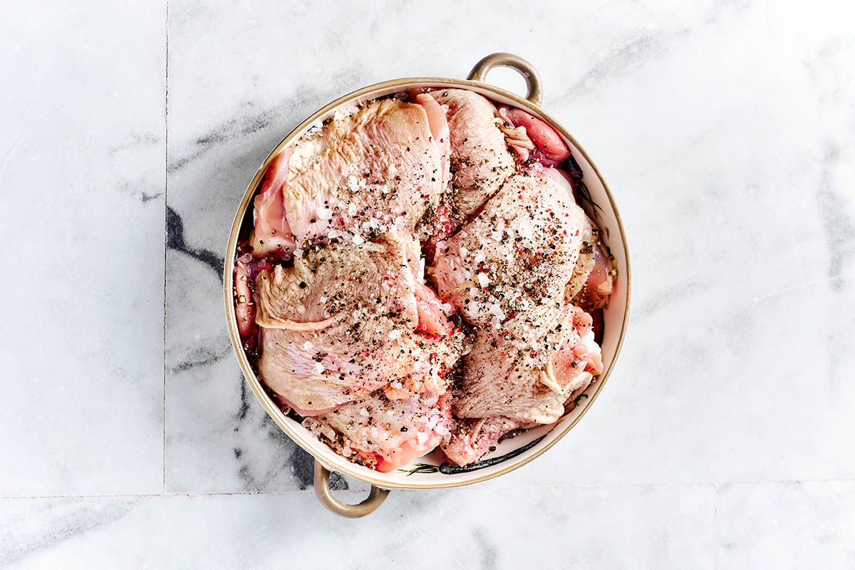 seasoned, raw chicken thighs in a bowl.