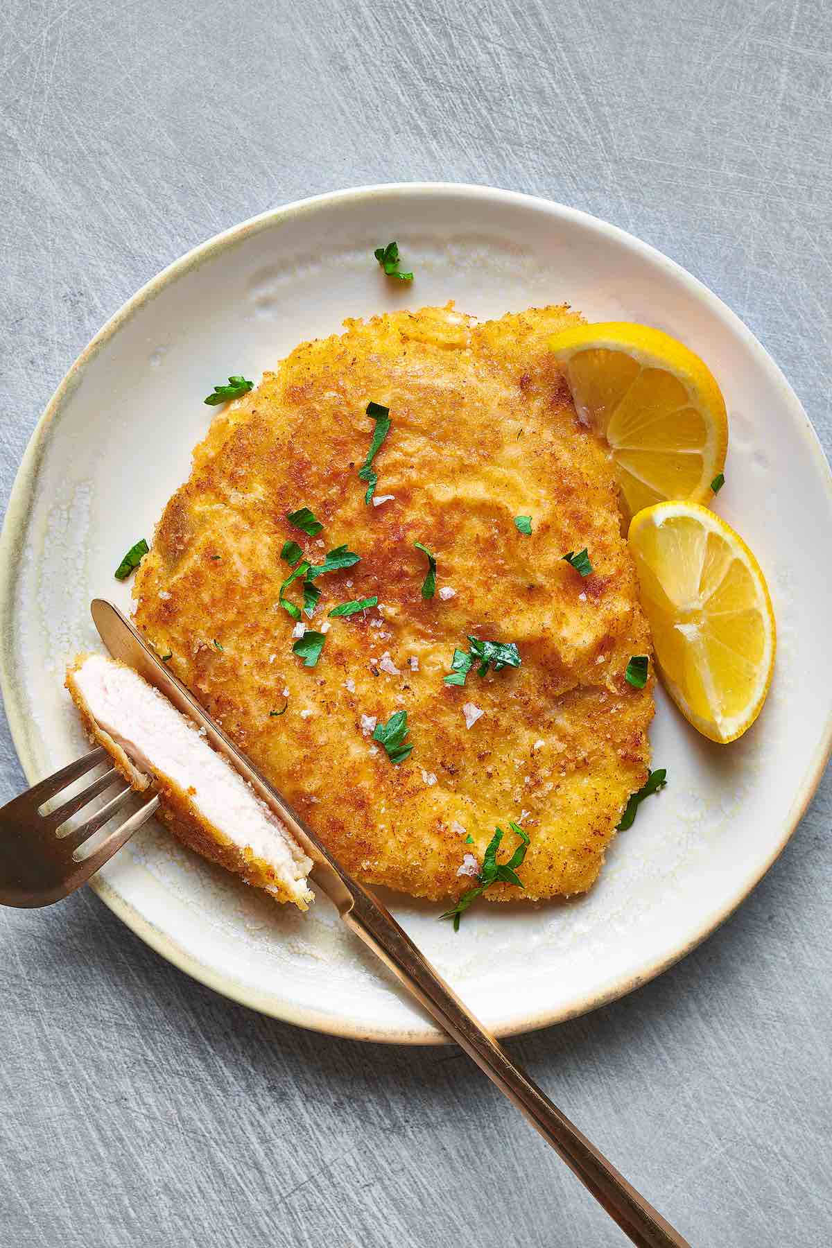 plate of chicken milanese with sliced lemon.