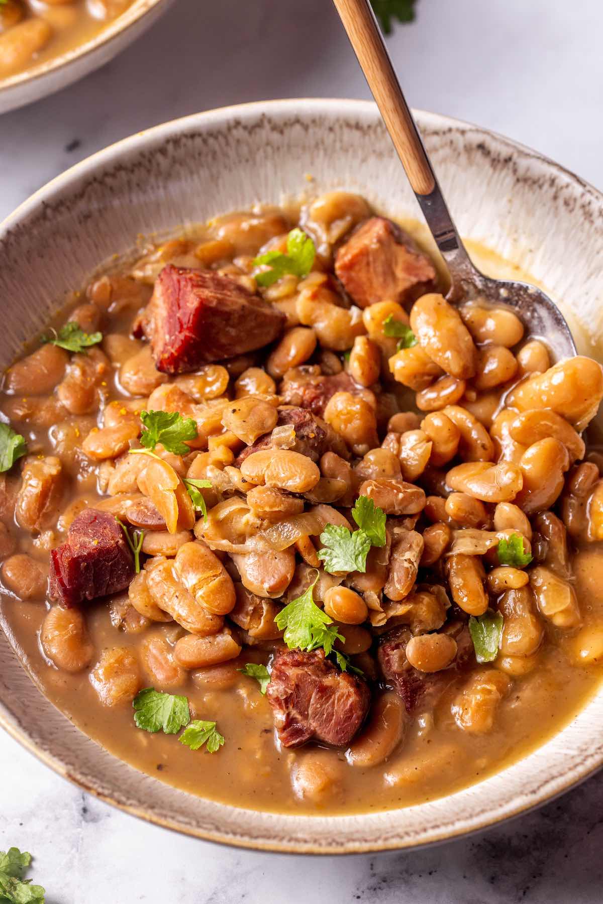 bowl of great northern beans with diced ham and fresh herbs.