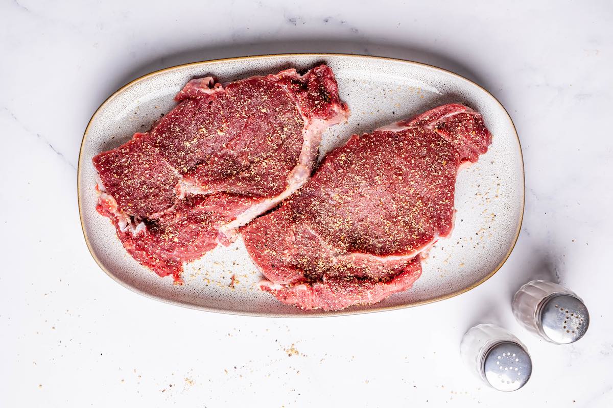 raw steaks with salt and pepper.