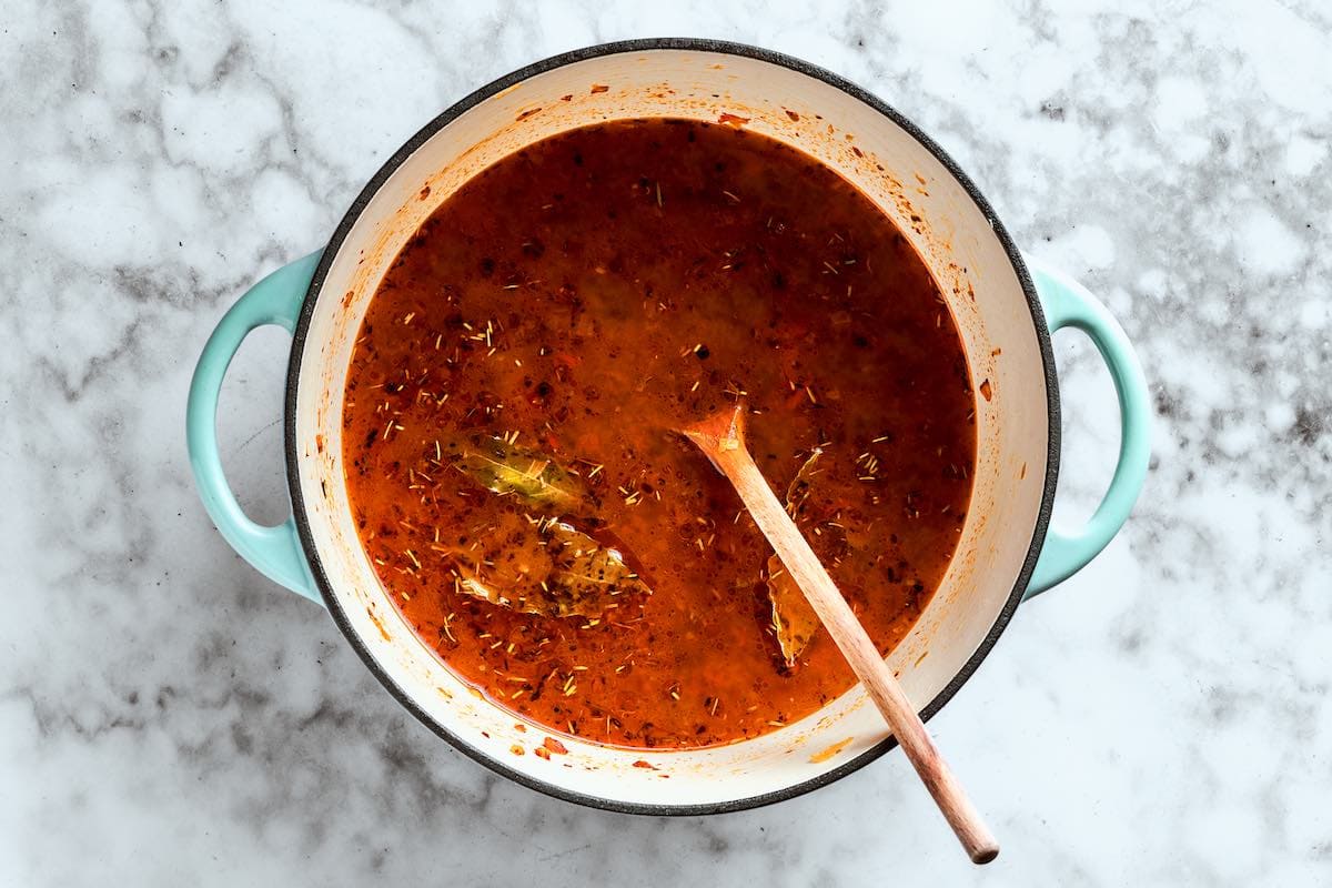 broth, herbs, and aromatics in a soup pot.