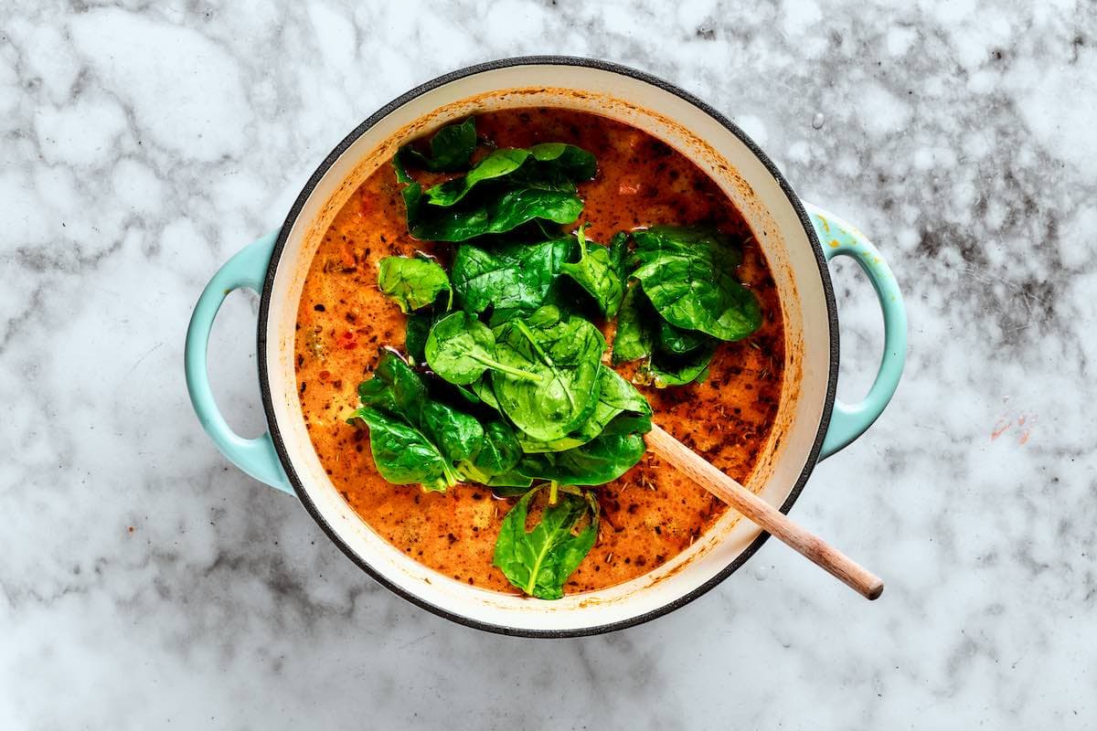 fresh baby spinach added to soup pot.