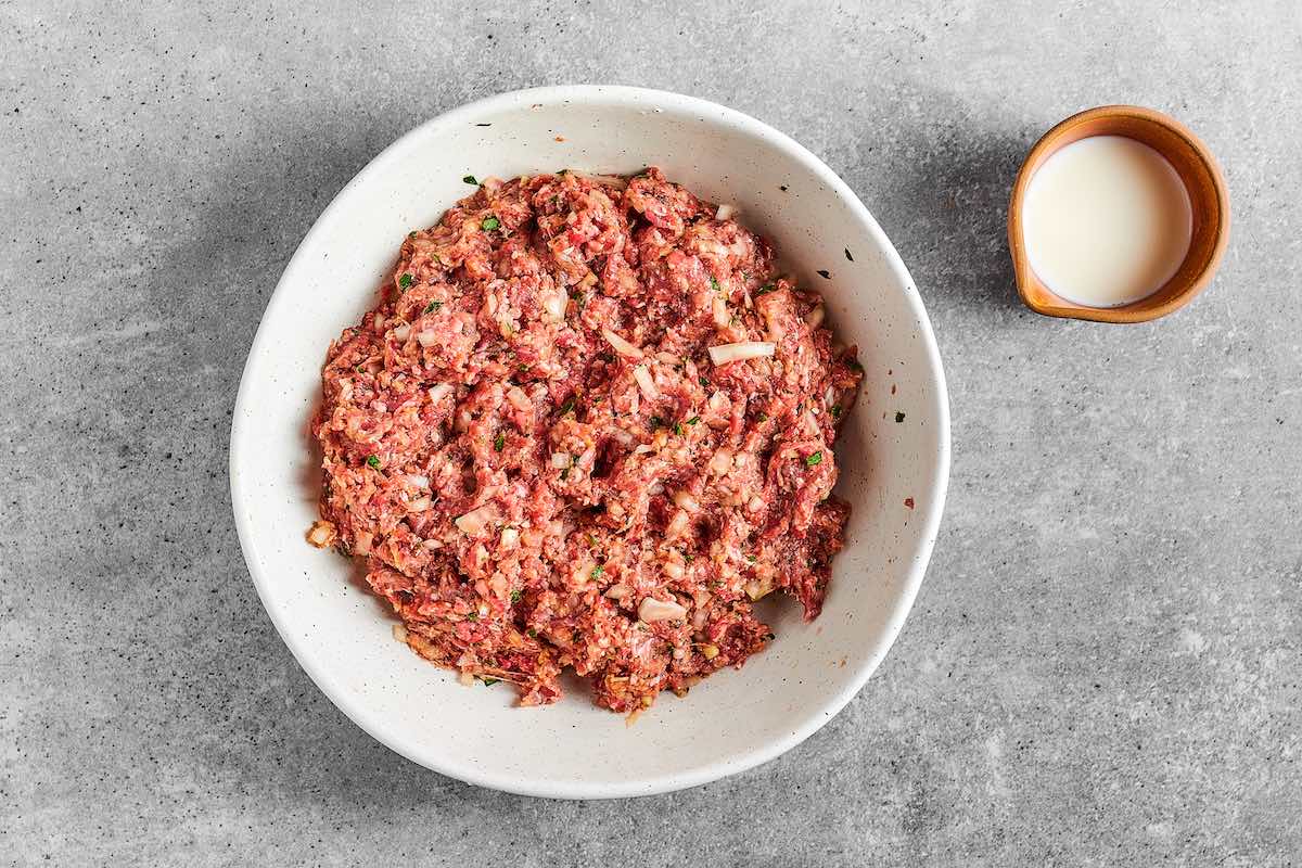 ground beef, seasonings, and onion in a bowl.