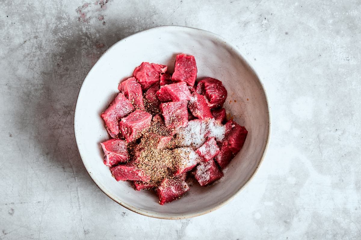 raw steak bites with seasonings in a bowl.