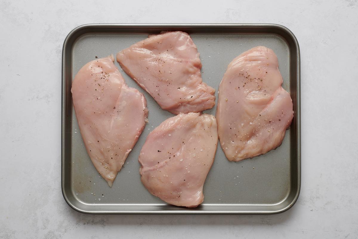 pounded raw chicken breasts on baking sheet.