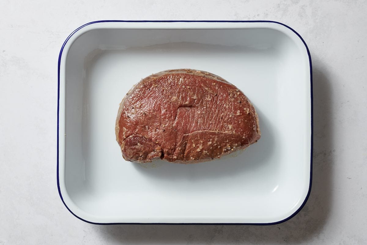 seasoned raw meat in roasting pan.