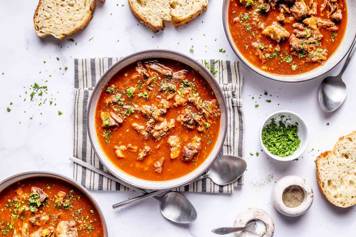 oxtail soup in bowls with fresh herbs on top.