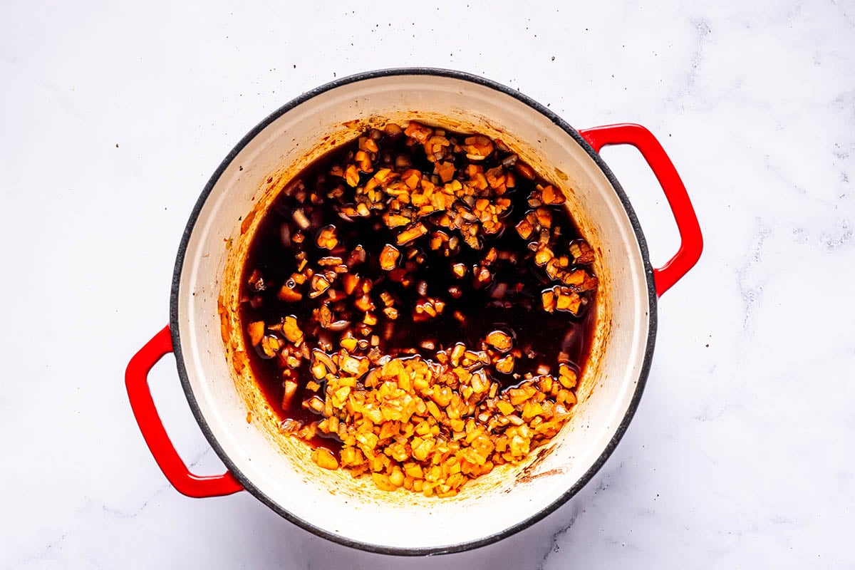 aromatics and sauce simmering in a Dutch oven.